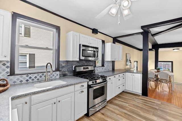 kitchen featuring stainless steel appliances, a sink, white cabinetry, light wood-type flooring, and crown molding