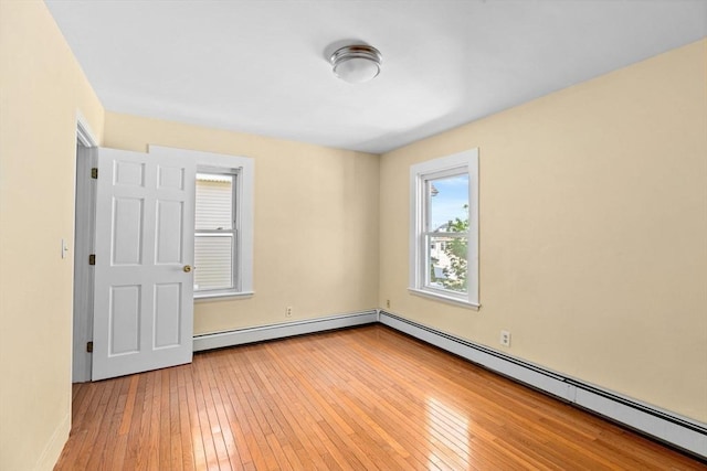 empty room featuring a baseboard heating unit and light wood finished floors