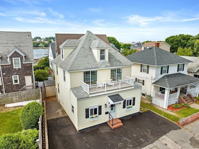 rear view of house featuring aphalt driveway, a residential view, and a balcony