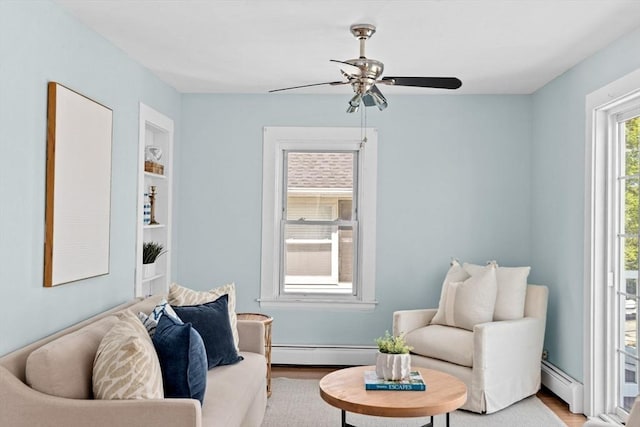 living area featuring light wood finished floors, baseboard heating, and a ceiling fan