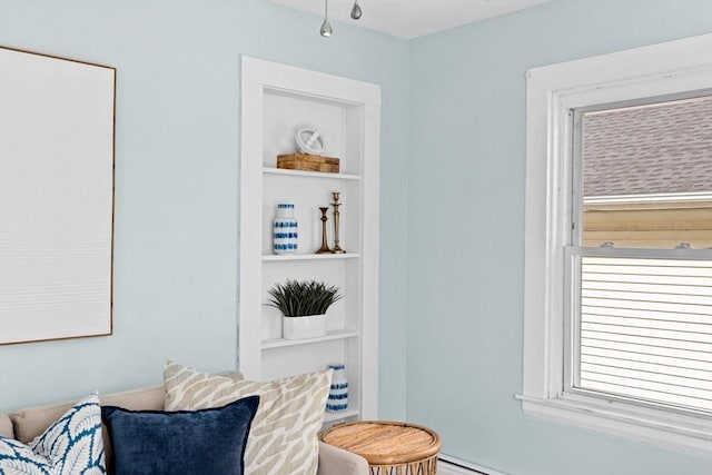 living area with built in shelves and baseboard heating