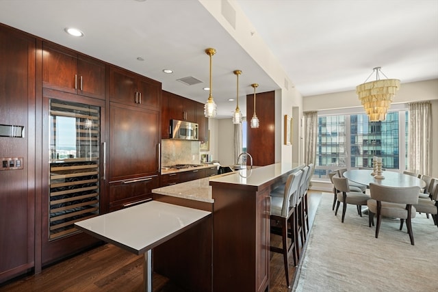 kitchen featuring an island with sink, pendant lighting, appliances with stainless steel finishes, and a chandelier