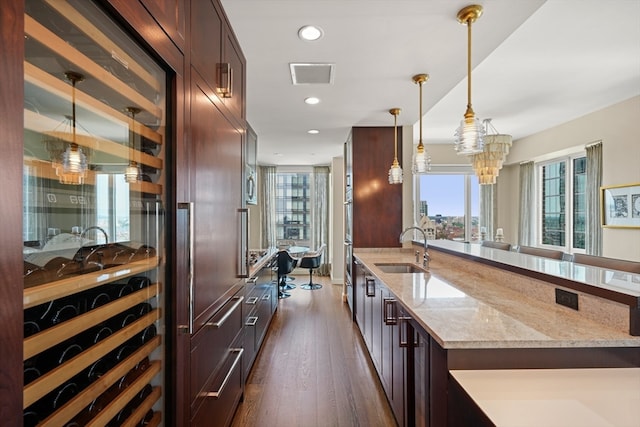 kitchen with dark hardwood / wood-style flooring, a healthy amount of sunlight, sink, and light stone countertops