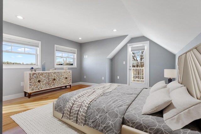 bedroom with multiple windows, access to outside, hardwood / wood-style flooring, and lofted ceiling