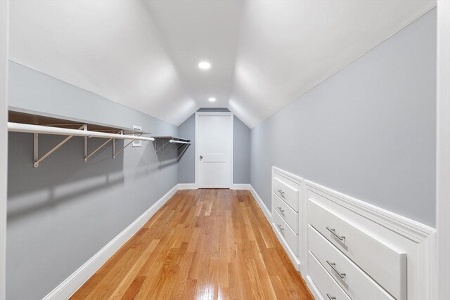 walk in closet featuring light wood-type flooring and vaulted ceiling