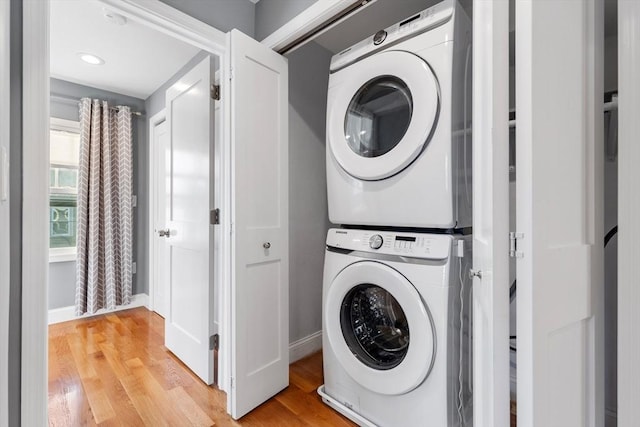 clothes washing area with stacked washer and dryer and light hardwood / wood-style flooring