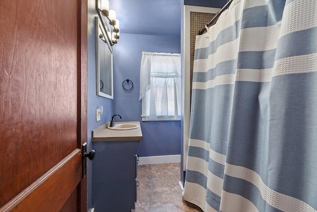 full bath with curtained shower, vanity, and baseboards