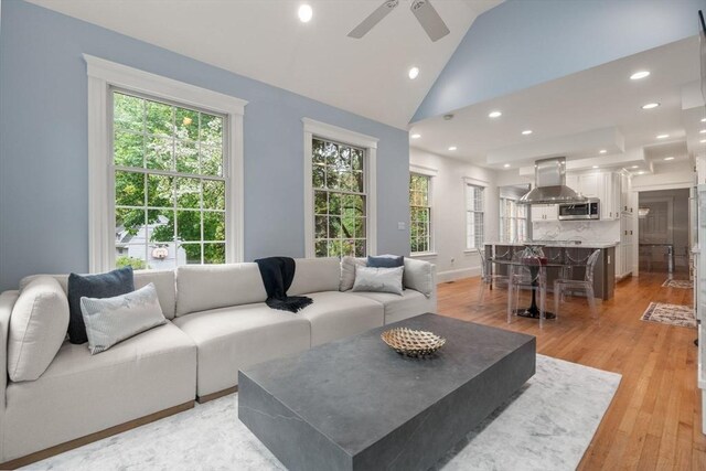 living room featuring a ceiling fan, light wood-type flooring, recessed lighting, high vaulted ceiling, and baseboards