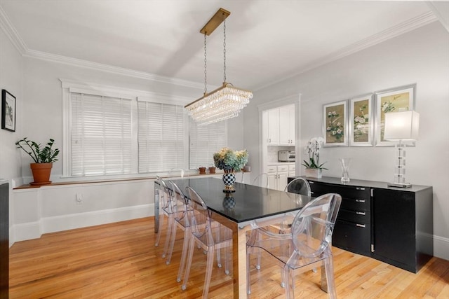 dining space featuring light wood-type flooring, crown molding, a chandelier, and baseboards