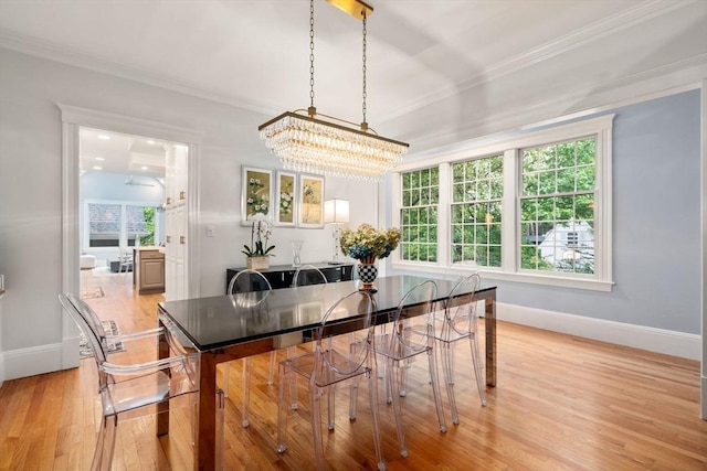 dining space with ornamental molding, a chandelier, light wood-style floors, baseboards, and plenty of natural light
