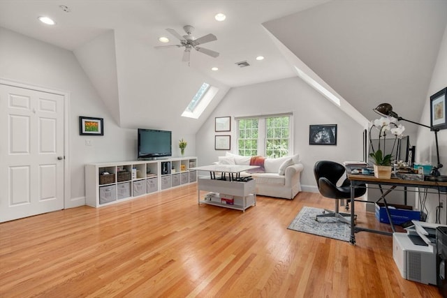 living room with a skylight, wood finished floors, a ceiling fan, lofted ceiling, and baseboards