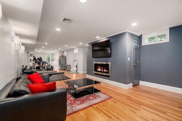 living area with light wood-type flooring, a glass covered fireplace, baseboards, and recessed lighting