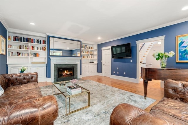 living area featuring a fireplace with flush hearth, wood finished floors, crown molding, baseboards, and recessed lighting