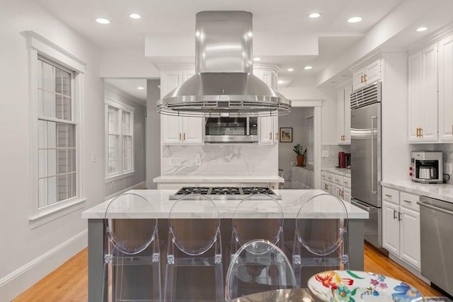 kitchen with island range hood, stainless steel appliances, white cabinetry, a center island, and light wood-style floors