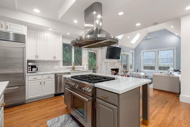 kitchen with high end appliances, open floor plan, a premium fireplace, ceiling fan, and recessed lighting