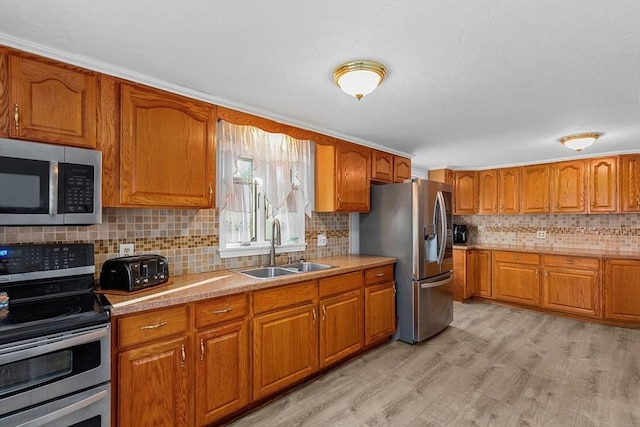 kitchen featuring decorative backsplash, appliances with stainless steel finishes, ornamental molding, sink, and light hardwood / wood-style floors