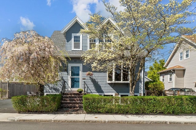 view of front facade featuring a shingled roof and fence private yard