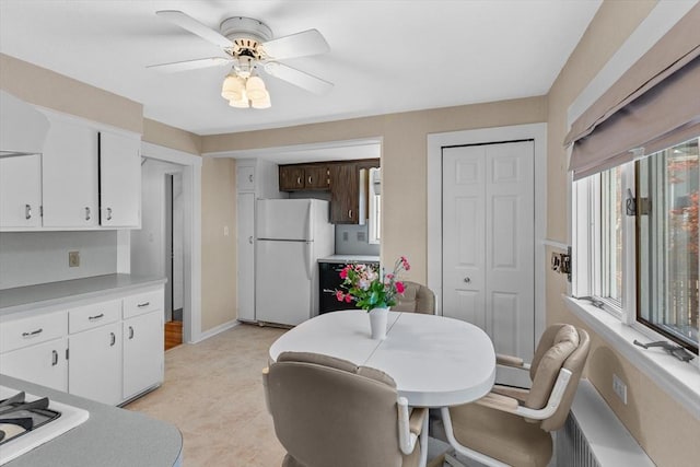 kitchen featuring freestanding refrigerator, white cabinetry, ceiling fan, and light countertops