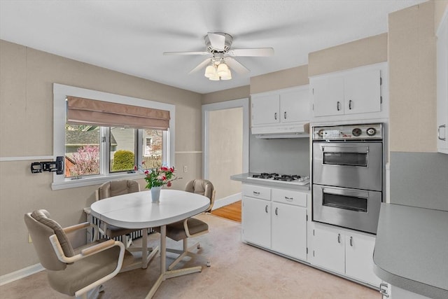 kitchen featuring stainless steel double oven, a ceiling fan, white gas stovetop, white cabinetry, and under cabinet range hood
