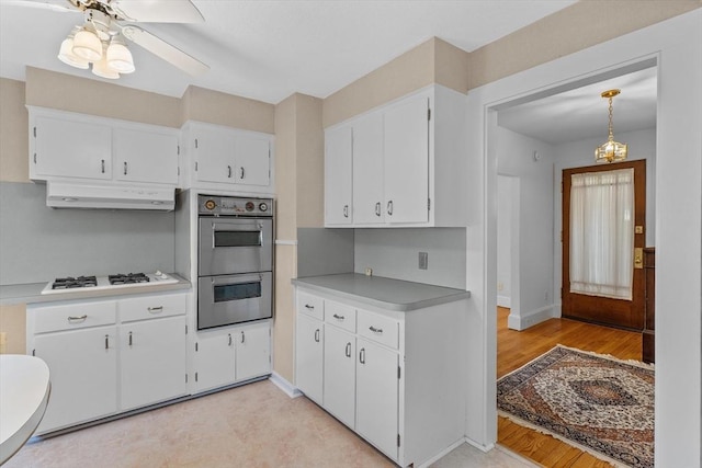 kitchen featuring light countertops, white cabinets, double wall oven, under cabinet range hood, and white gas stovetop
