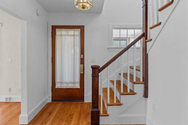 entryway with stairs, baseboards, a chandelier, and wood finished floors