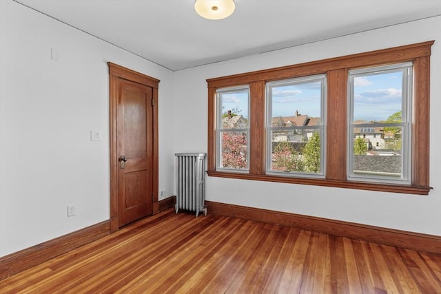 empty room featuring baseboards, light wood finished floors, and radiator