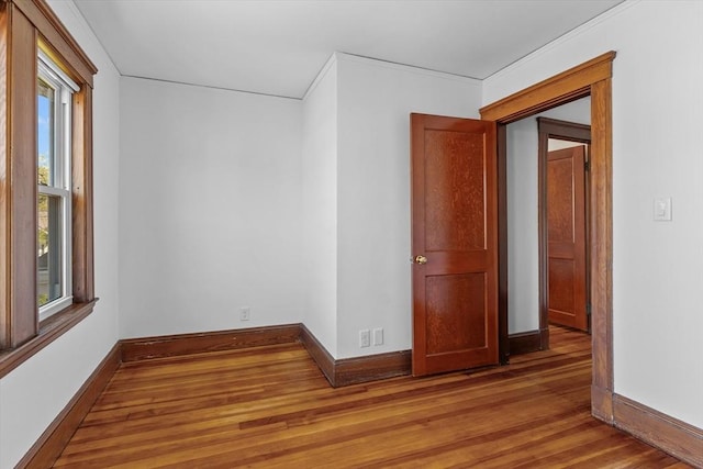 empty room with baseboards, ornamental molding, and wood finished floors