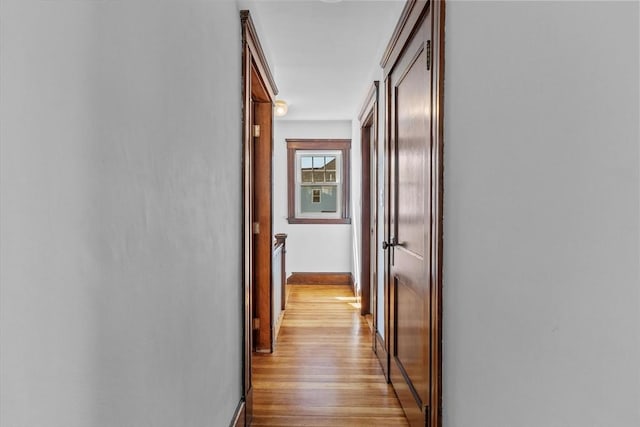 hall with baseboards and light wood-style flooring