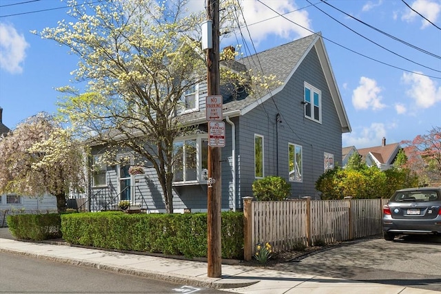view of front of home with a shingled roof and fence