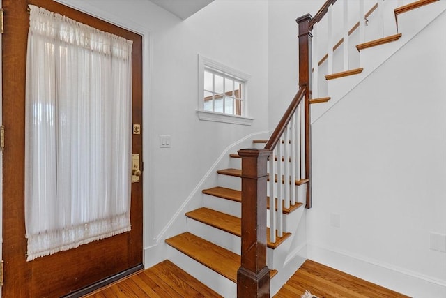 foyer entrance featuring baseboards, stairs, and wood finished floors