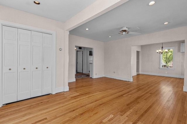 unfurnished living room with baseboards, ceiling fan with notable chandelier, recessed lighting, and light wood-style flooring