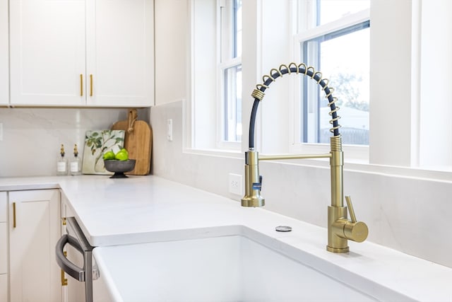 details with decorative backsplash, sink, and white cabinets