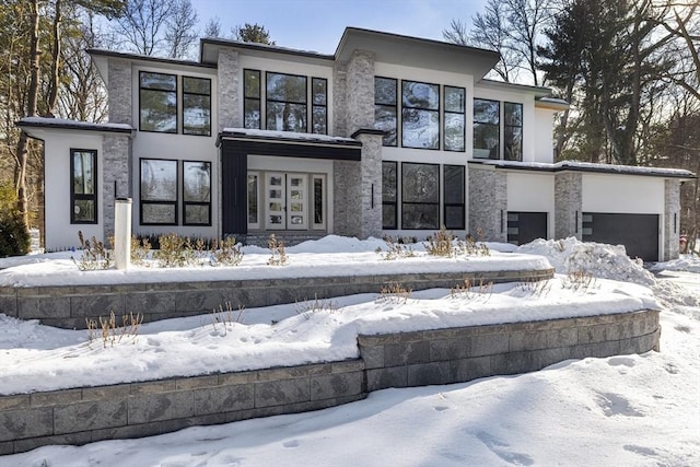 snow covered property with a garage and stucco siding