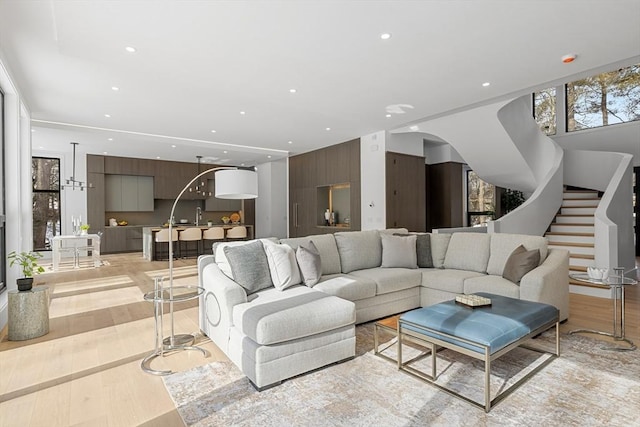 living room with light wood-type flooring, arched walkways, recessed lighting, and stairs