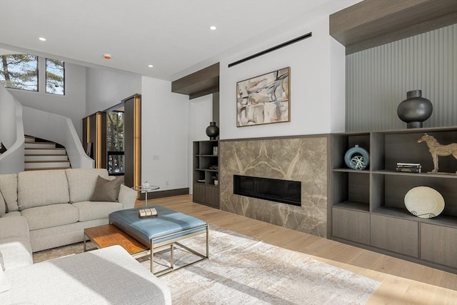 living area featuring stairway, recessed lighting, a fireplace, and light wood-style flooring