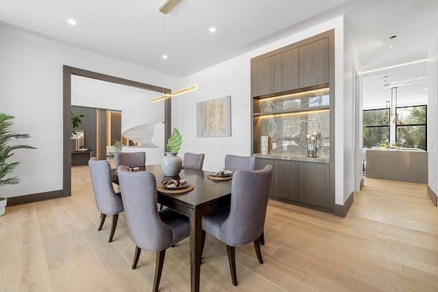 dining space featuring baseboards, light wood finished floors, and recessed lighting