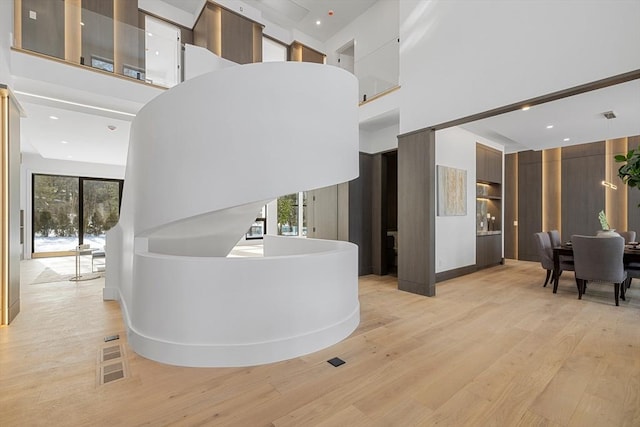 hallway featuring light wood finished floors, a high ceiling, and recessed lighting