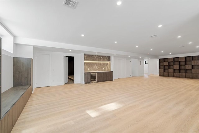 unfurnished living room featuring indoor bar, light wood-type flooring, visible vents, and recessed lighting