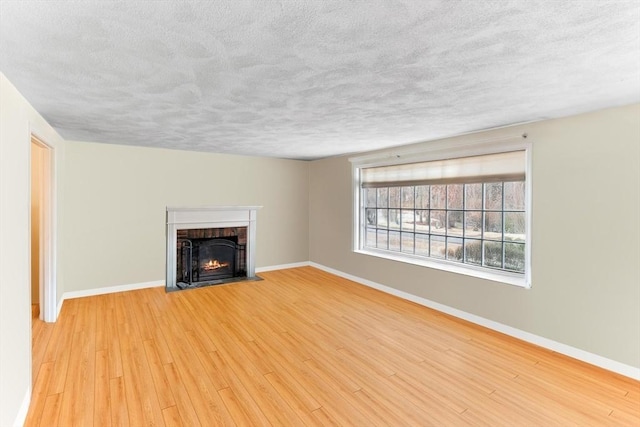 unfurnished living room with a fireplace, light hardwood / wood-style flooring, and a textured ceiling