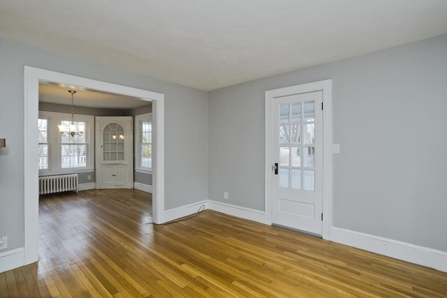 entryway with baseboards, an inviting chandelier, radiator heating unit, and hardwood / wood-style flooring