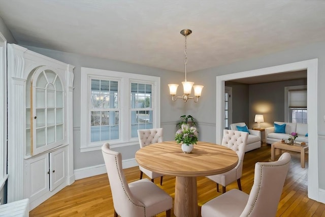 dining room featuring baseboards, light wood-type flooring, and an inviting chandelier