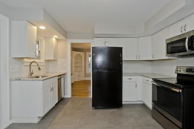 kitchen featuring a sink, light stone countertops, appliances with stainless steel finishes, and white cabinets