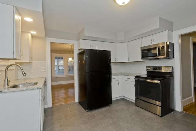 kitchen with white cabinetry, light stone countertops, stainless steel appliances, and a sink