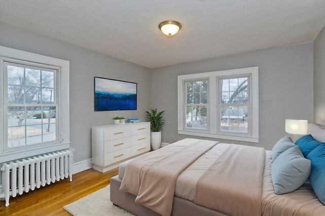 bedroom with light wood-style flooring, radiator, and baseboards