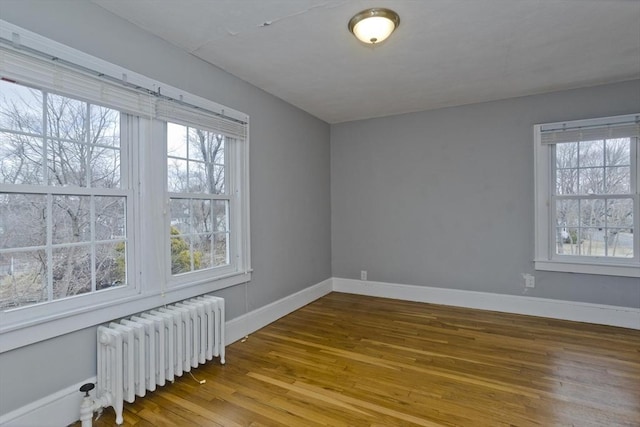 unfurnished room with radiator heating unit, baseboards, and wood-type flooring