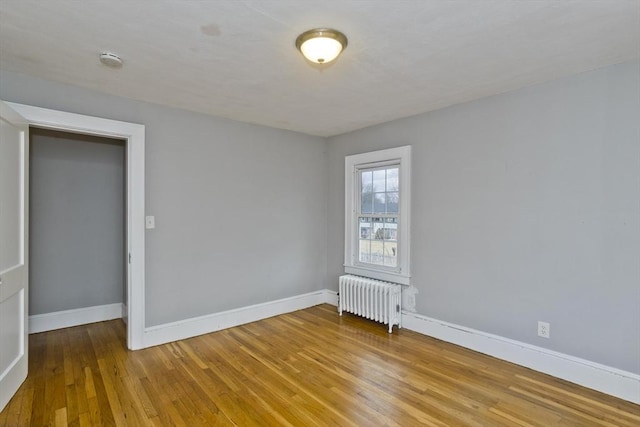 empty room with radiator, baseboards, and wood-type flooring