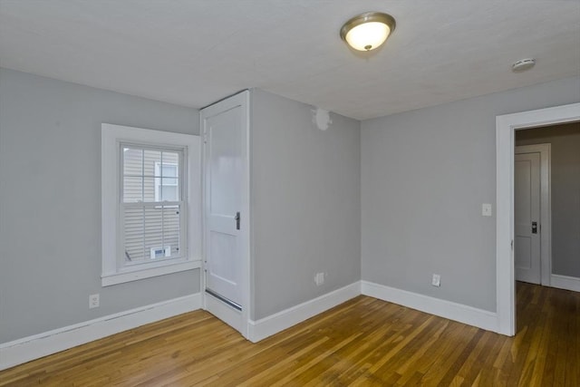 empty room with baseboards and wood finished floors