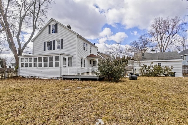 back of house with a lawn, a deck, fence, a sunroom, and a chimney