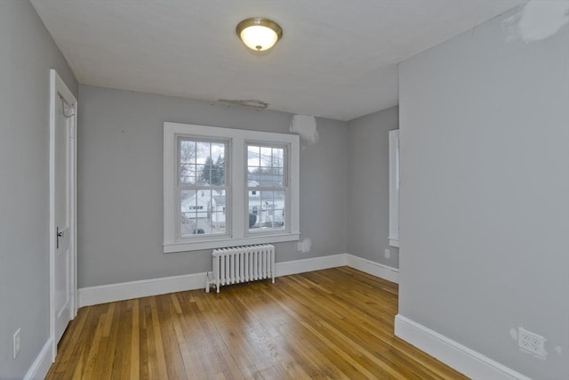 unfurnished room featuring radiator, baseboards, and wood-type flooring