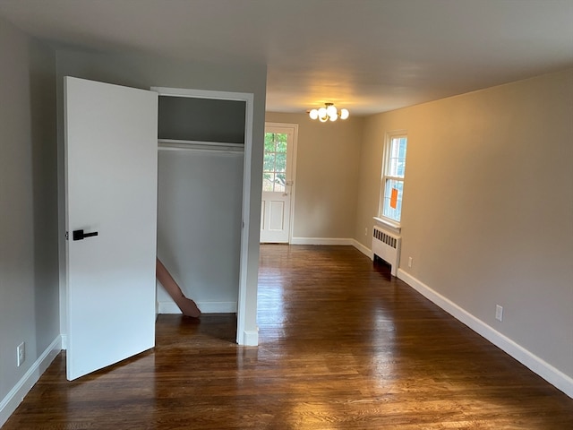 unfurnished bedroom with dark hardwood / wood-style floors, radiator heating unit, and a closet